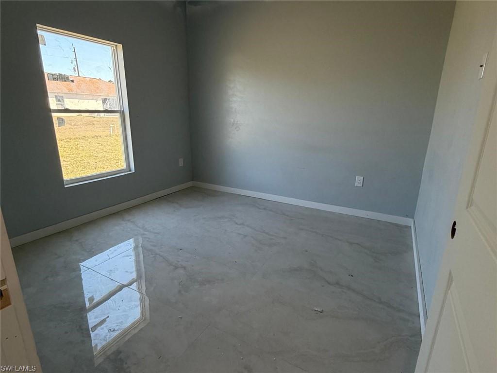 Empty room with baseboards and unfinished concrete flooring