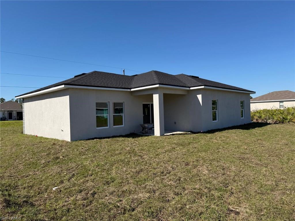 Back of house featuring stucco siding, a yard, and a patio