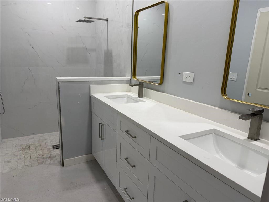 Bathroom with double vanity and a marble finish shower