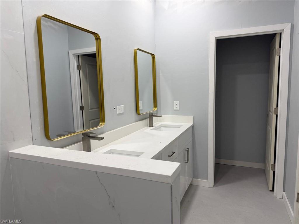 Bathroom with double vanity and finished concrete flooring