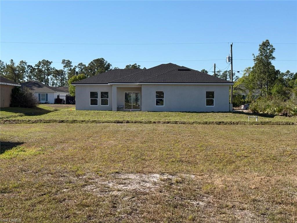 Rear view of house featuring a yard, stucco siding, and a patio