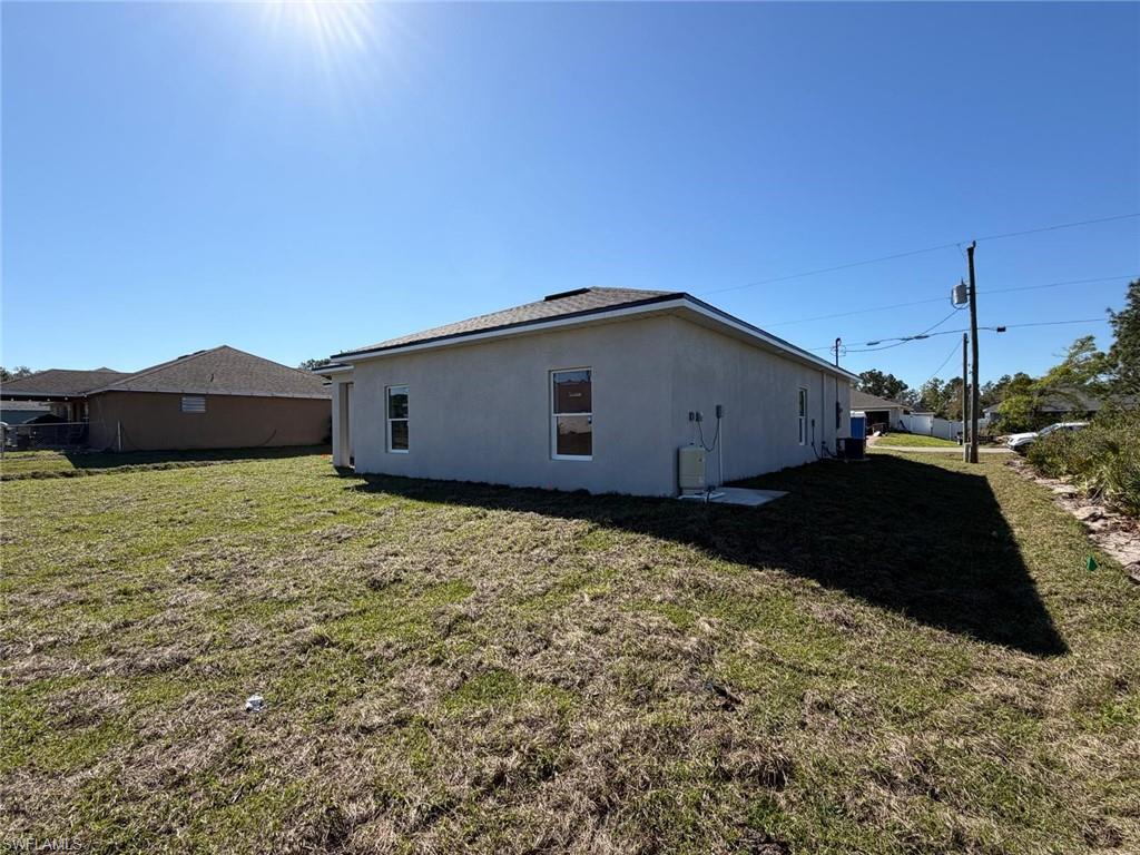View of side of home featuring a lawn and stucco siding