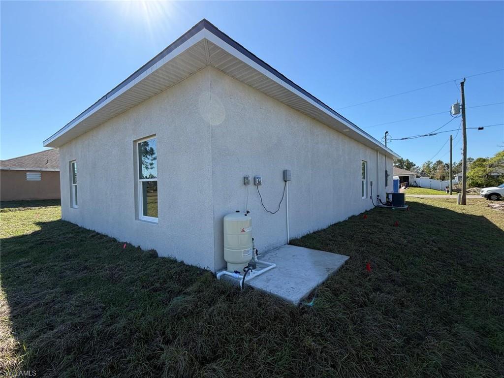View of property exterior with a yard, stucco siding, and a patio area