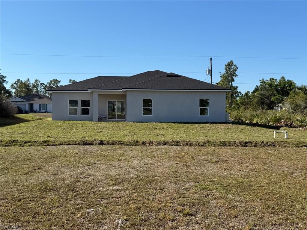Rear view of property with stucco siding and a lawn