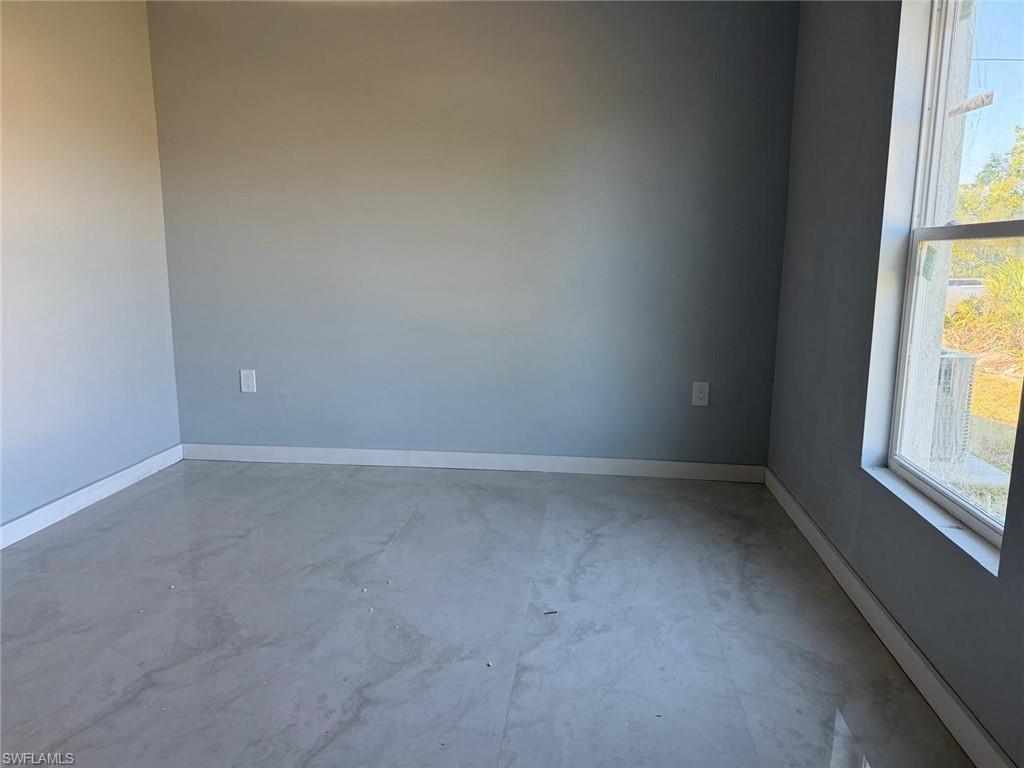 Unfurnished room featuring concrete flooring and baseboards