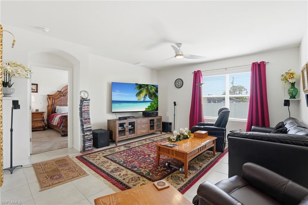 Living area with light tile patterned floors, ceiling fan, and arched walkways