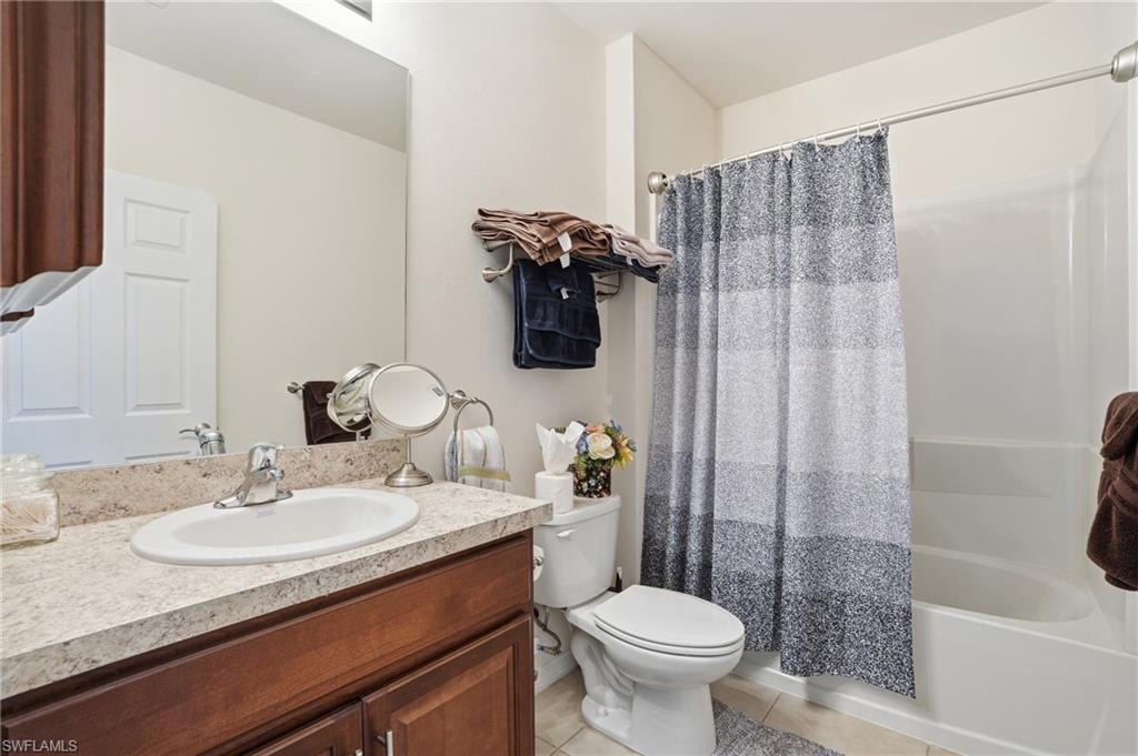 Full bath featuring shower / tub combo with curtain, vanity, and light tile patterned floors