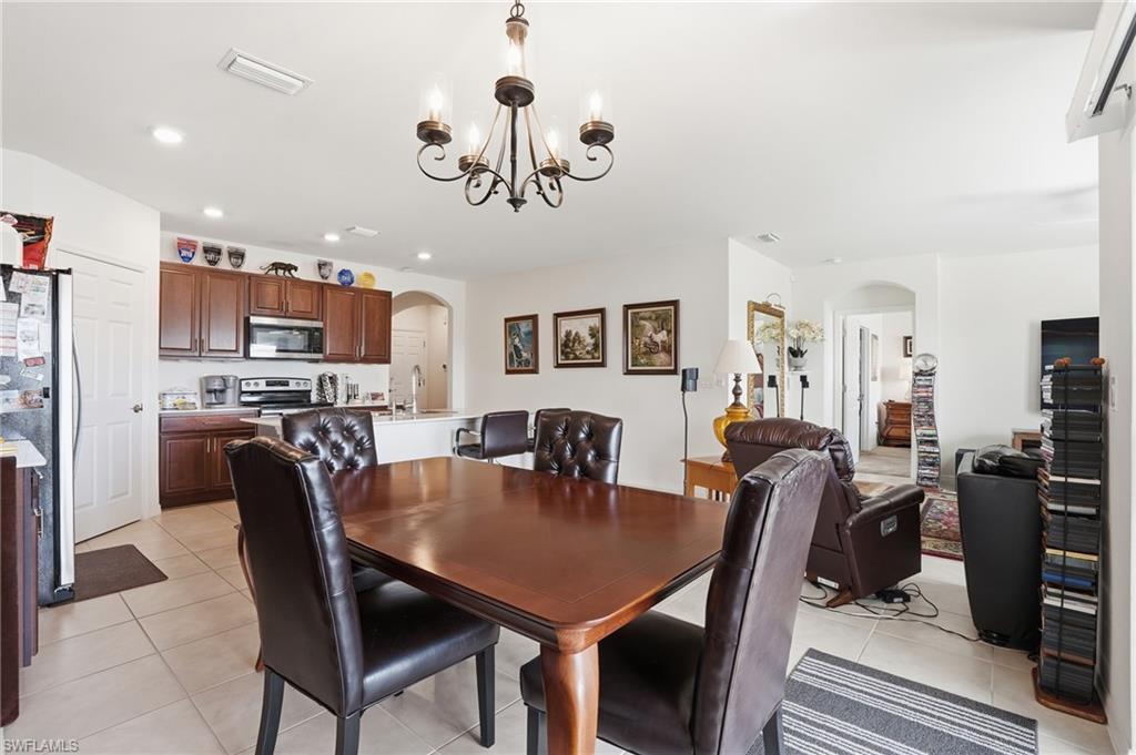 Dining area with arched walkways, hanging lights, and light tile patterned floors