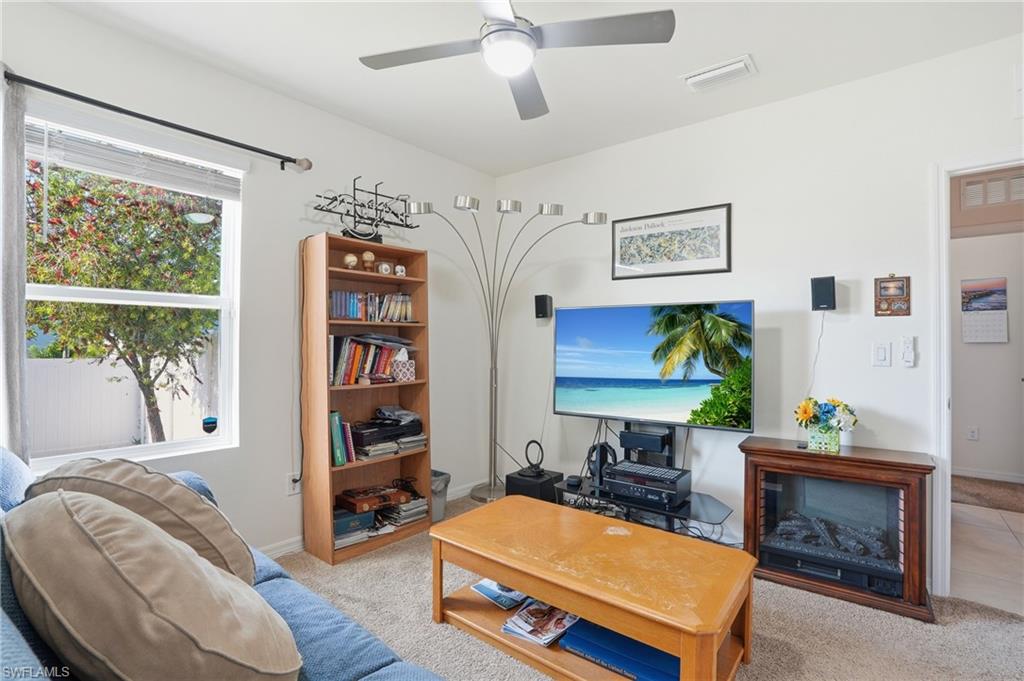 Living area with light colored carpet and a ceiling fan