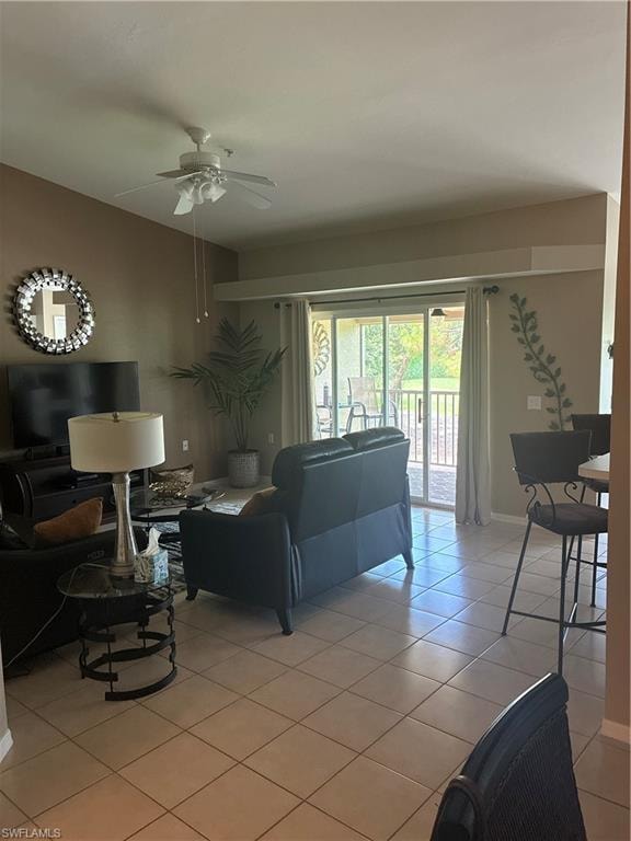 Open-concept living area with neutral tile flooring, ceiling fan with light fixture, and direct access to an outdoor space via sliding glass doors