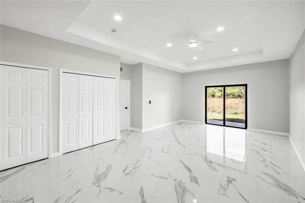 Unfurnished bedroom with recessed lighting, multiple closets, a raised ceiling, and ceiling fan