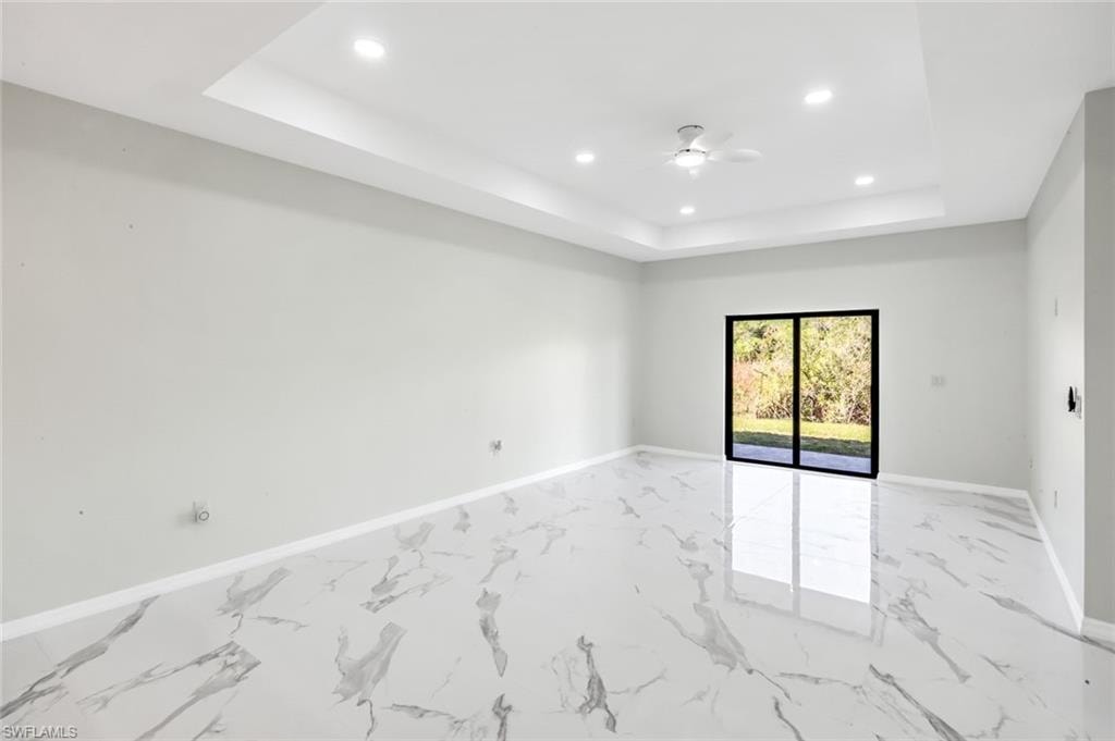 Unfurnished room with recessed lighting, a ceiling fan, light marble finish floors, and a raised ceiling