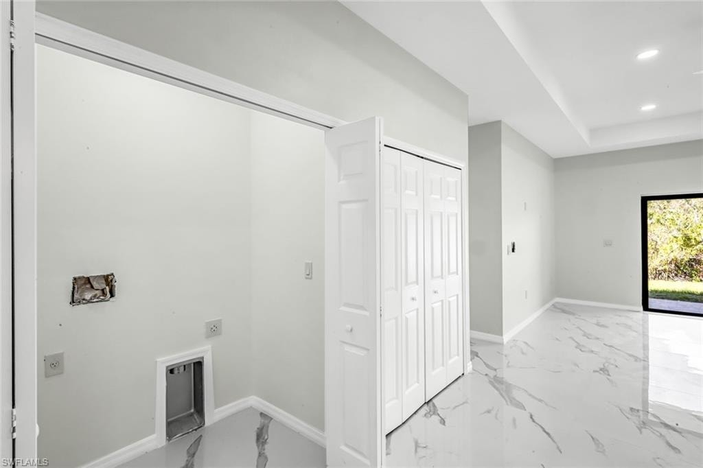 Laundry area with recessed lighting, electric dryer hookup, a raised ceiling, and light marble finish floors