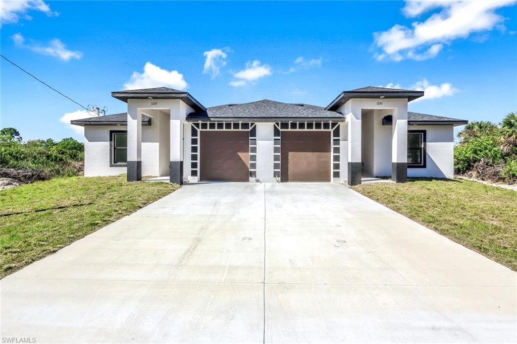 Prairie-style house with stucco siding, an attached garage, concrete driveway, and a front yard