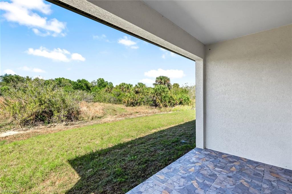 View of grassy yard featuring a patio