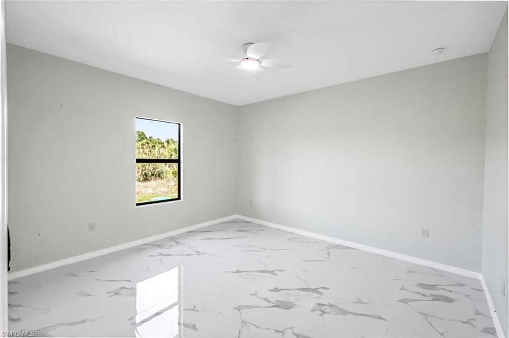 Empty room featuring ceiling fan and light marble finish floors