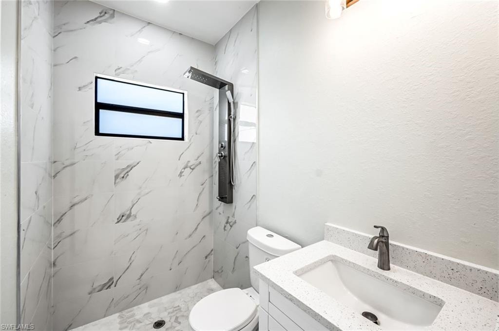 Full bathroom featuring vanity and a marble finish shower