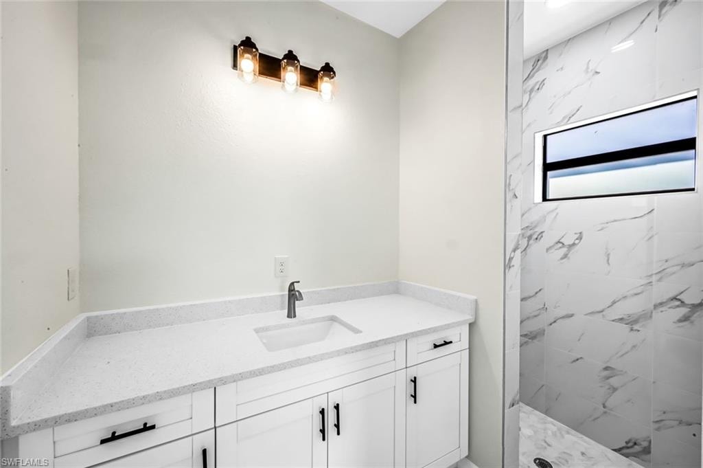 Full bathroom featuring vanity and a marble finish shower