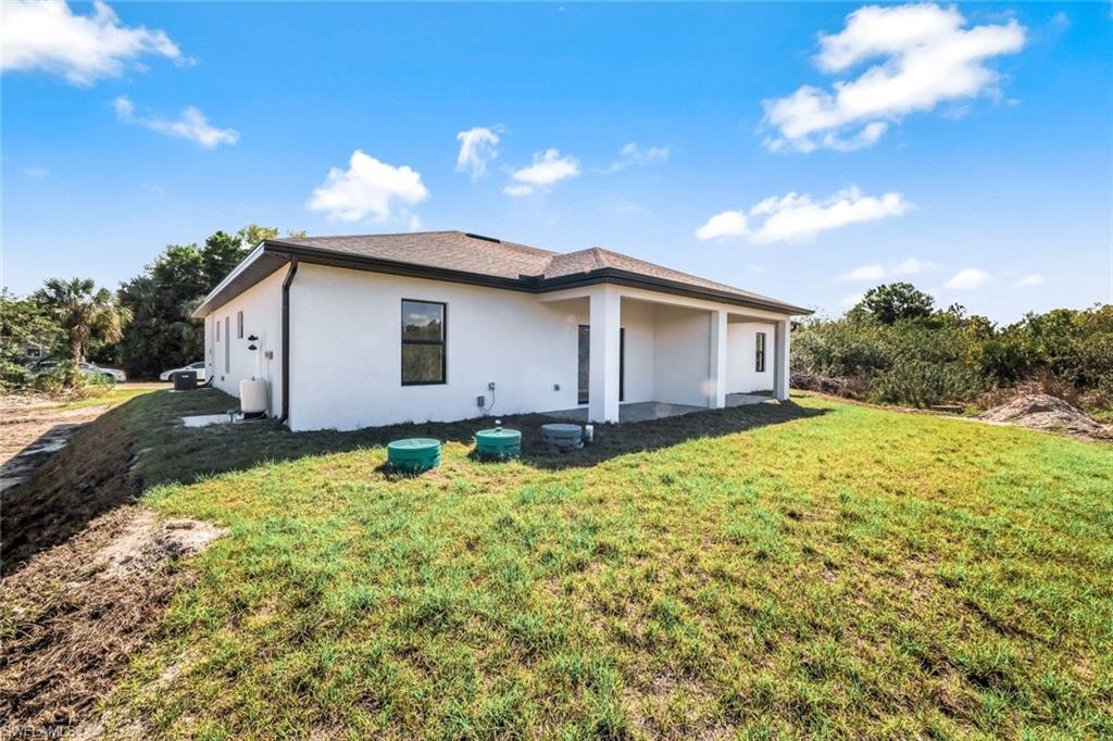 Back of house featuring a lawn, stucco siding, and a patio