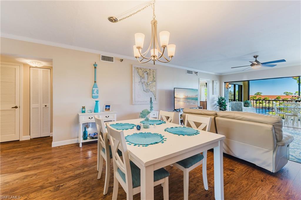 Dining area featuring crown molding, dark wood finished floors, a chandelier, and ceiling fan