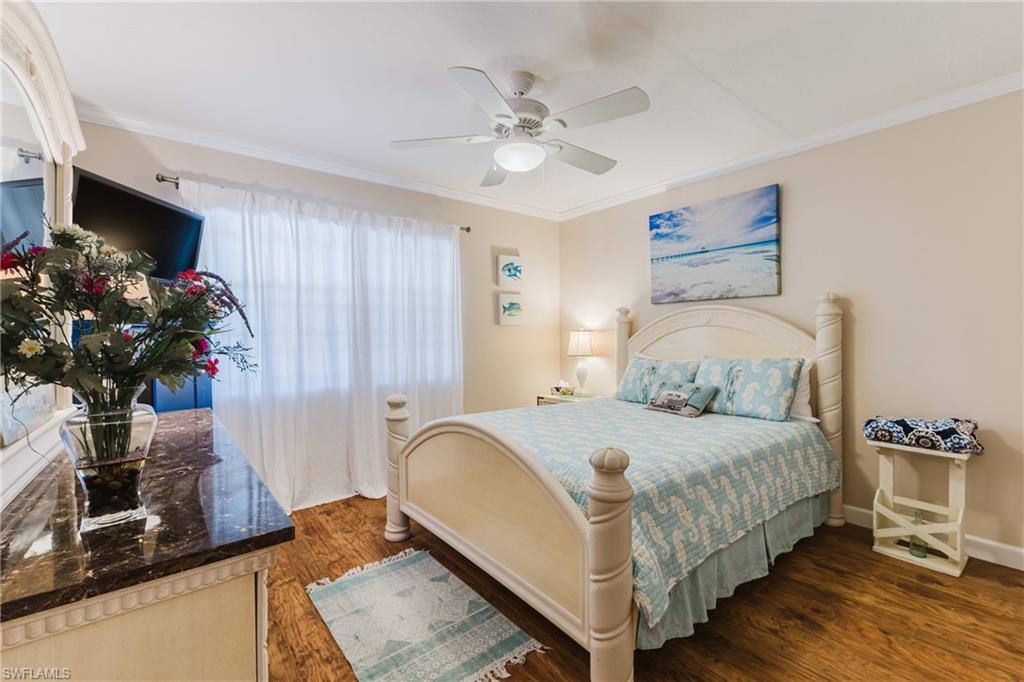 Bedroom with dark wood-style floors, crown molding, and ceiling fan