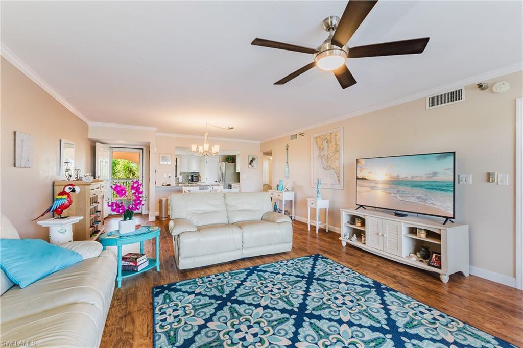 Living area featuring hanging lights, dark wood finished floors, crown molding, and ceiling fan