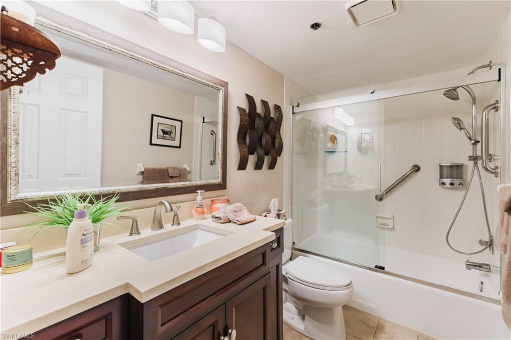 Bathroom with vanity, shower / bath combination with glass door, and light tile patterned flooring
