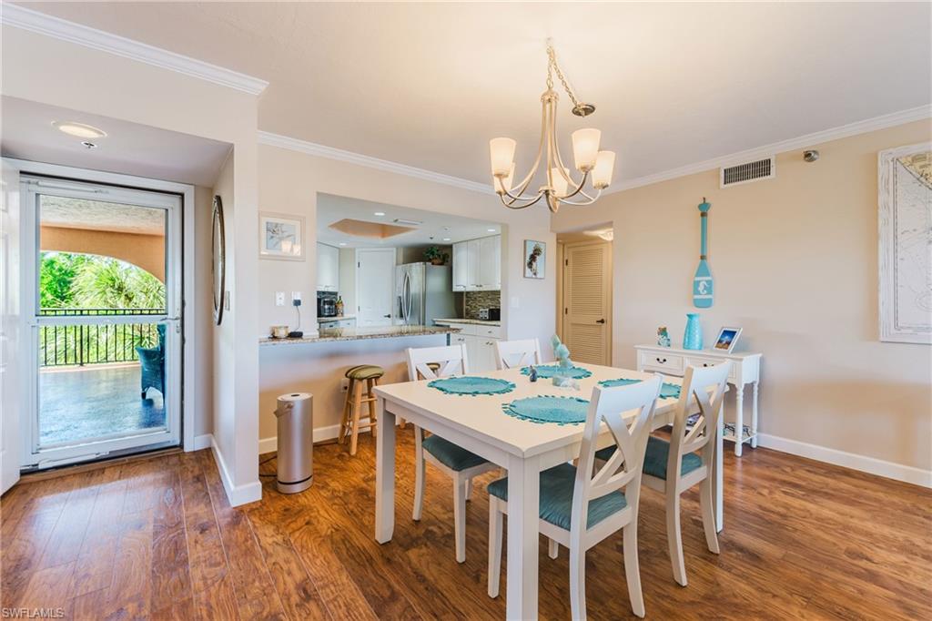 Dining area with hanging lights, dark wood finished floors, and crown molding