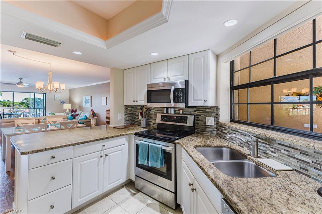 Kitchen featuring stainless steel appliances, a peninsula, light stone counters, white cabinets, and open floor plan