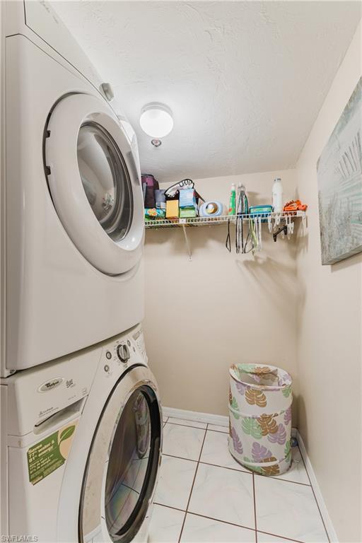 Laundry room featuring stacked washer / drying machine and a textured ceiling