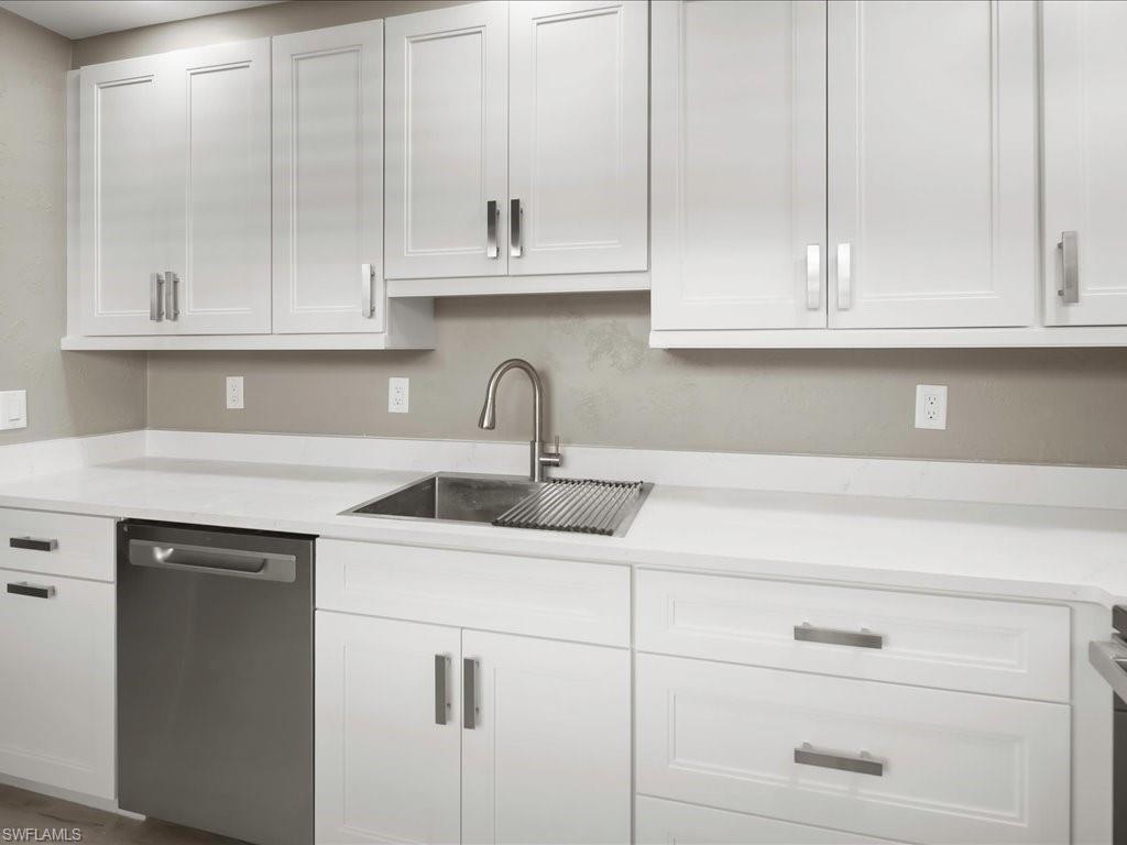 Kitchen with white cabinetry, stainless steel dishwasher, and light stone countertops