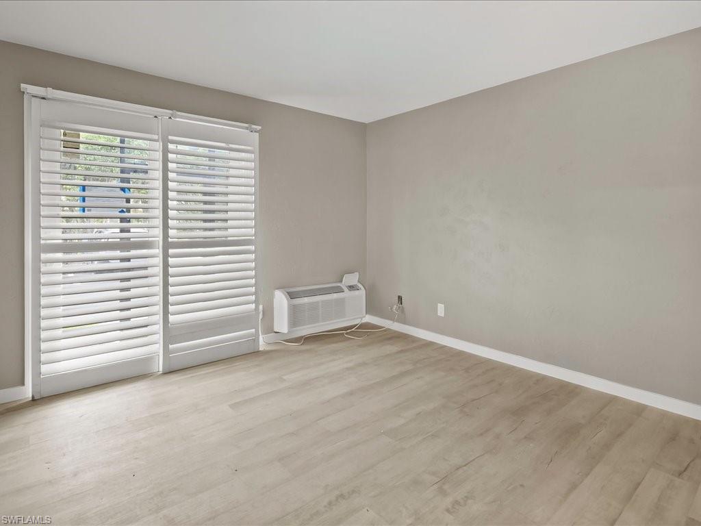 Unfurnished room featuring light wood finished floors and an AC wall unit