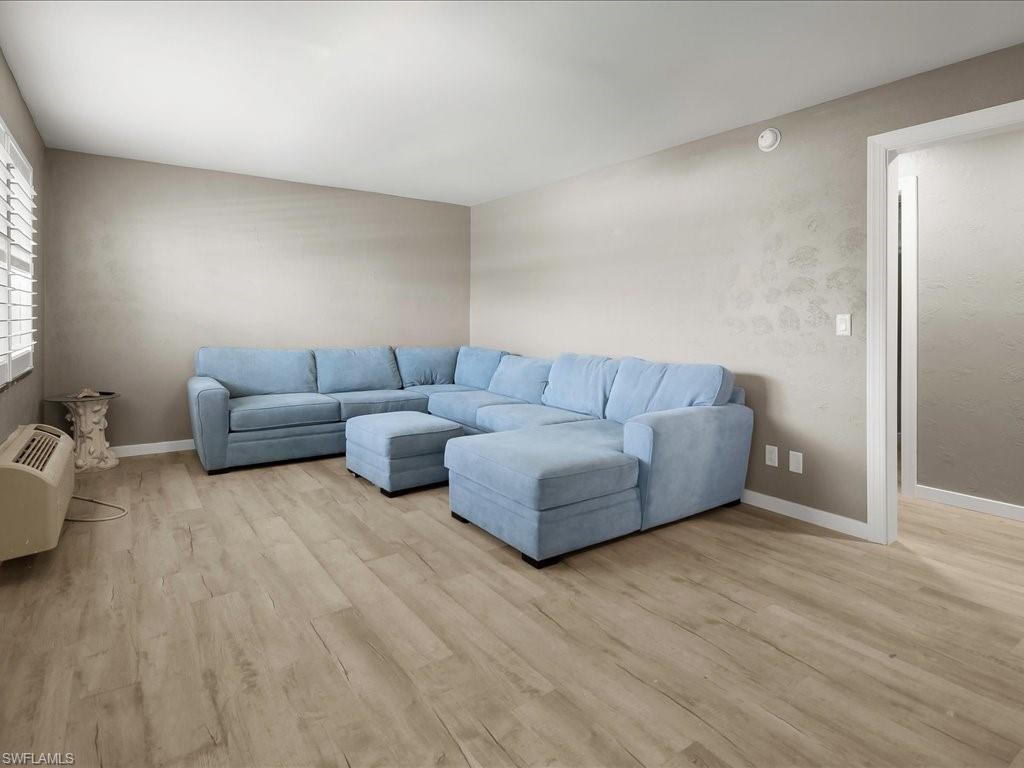 Living area featuring light wood-style flooring and a wall mounted air conditioner