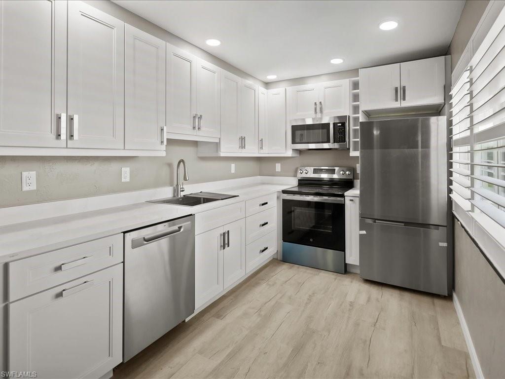Kitchen with appliances with stainless steel finishes, white cabinetry, recessed lighting, and light wood finished floors