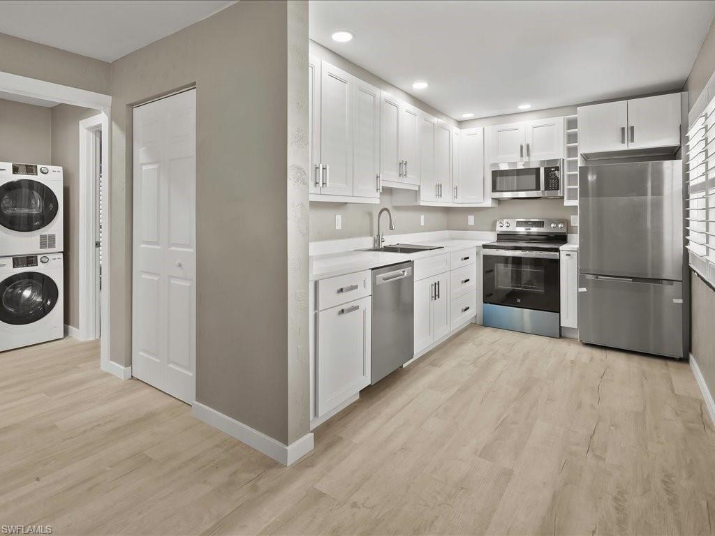 Kitchen with stainless steel appliances, white cabinetry, light wood finished floors, and recessed lighting