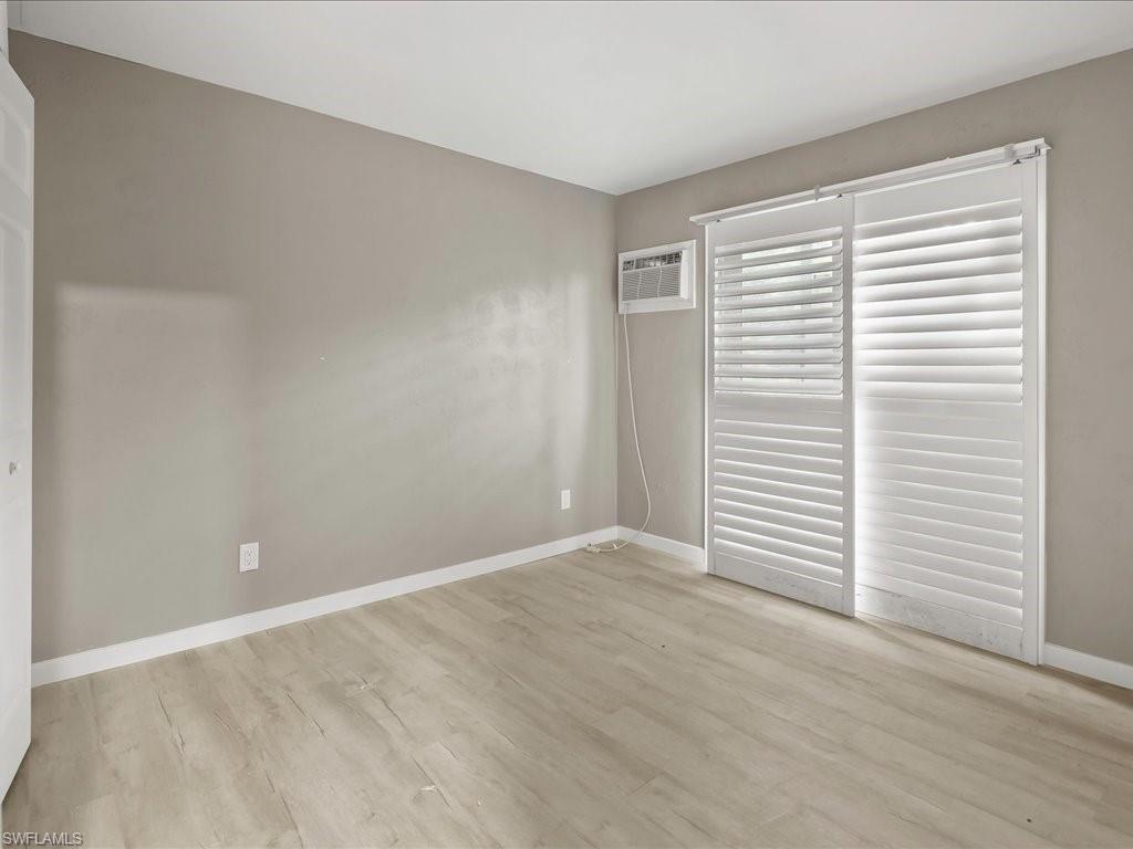 Unfurnished bedroom featuring light wood finished floors and a wall mounted air conditioner