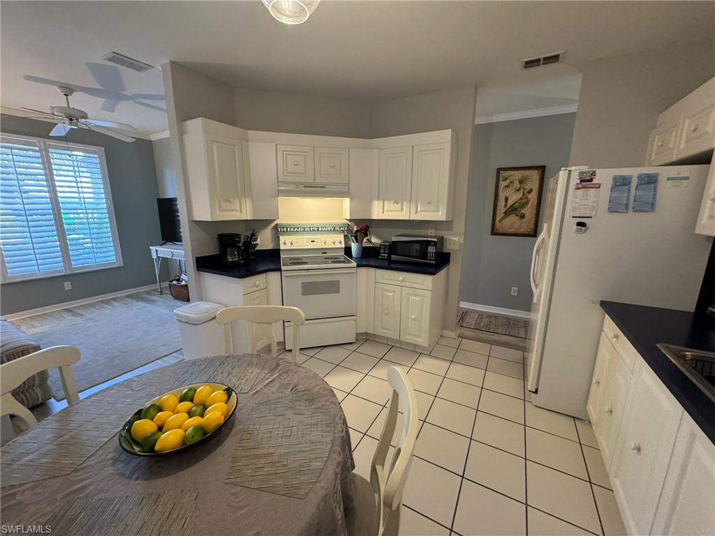 Kitchen featuring ornamental molding, white cabinets, ceiling fan, and white appliances