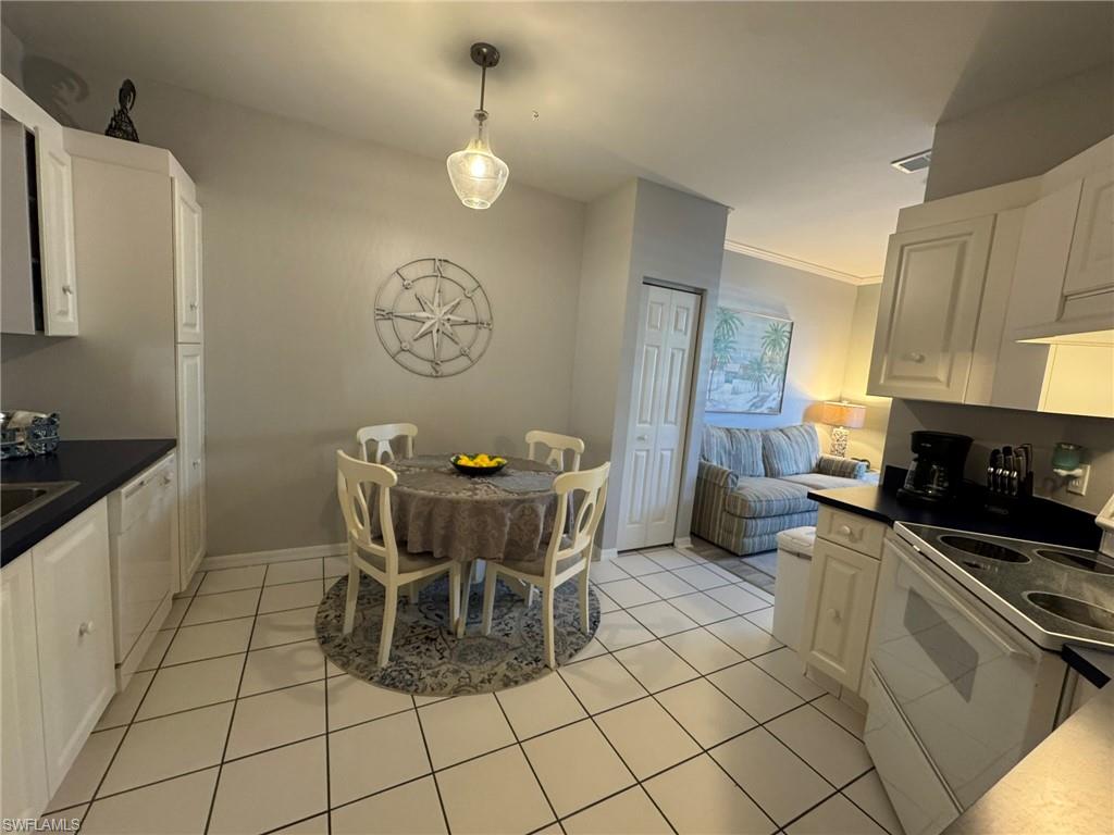 Kitchen featuring white cabinets, hanging light fixtures, light tile patterned floors, crown molding, and white appliances