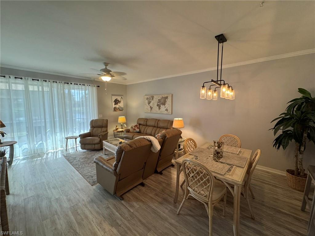 Living room with crown molding, ceiling fan with notable chandelier, and hardwood / wood-style floors