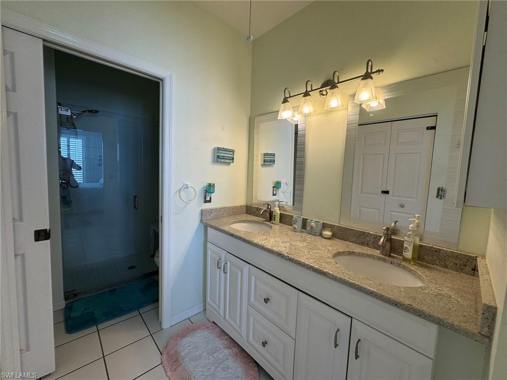 Bathroom featuring a shower with door, toilet, tile patterned flooring, and vanity