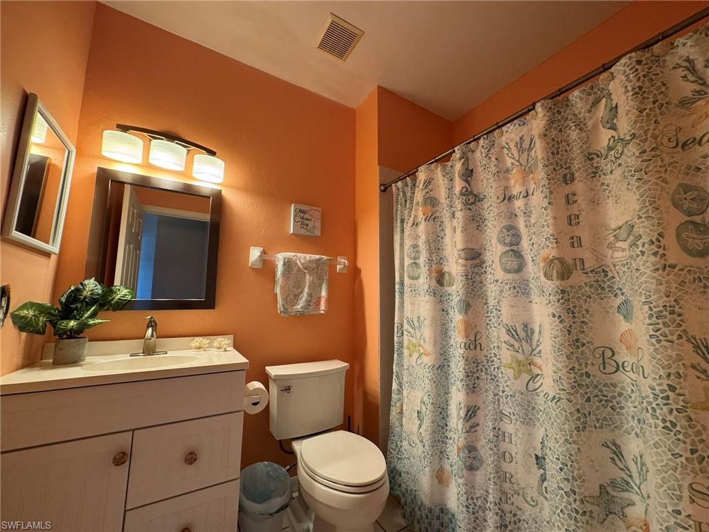 Bathroom with vanity, a shower with curtain, and toilet