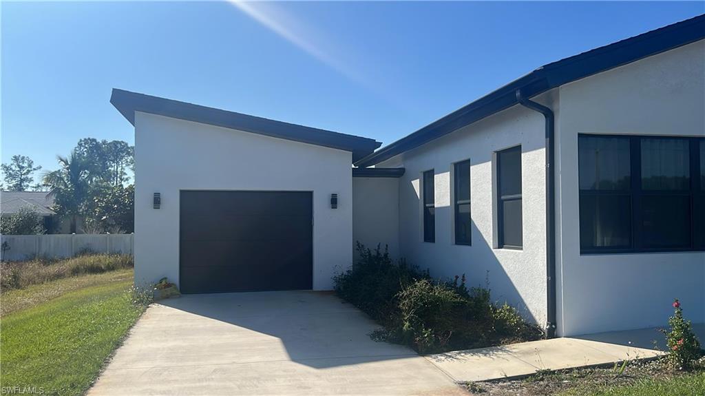 View of front of property with stucco siding, driveway, and an attached garage