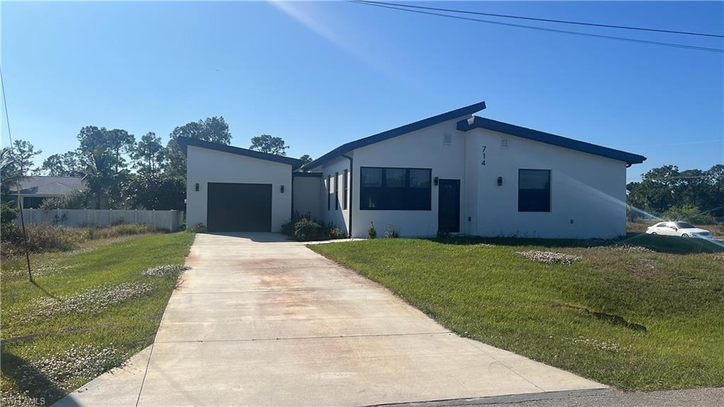 View of front of home with concrete driveway, a front yard, and stucco siding