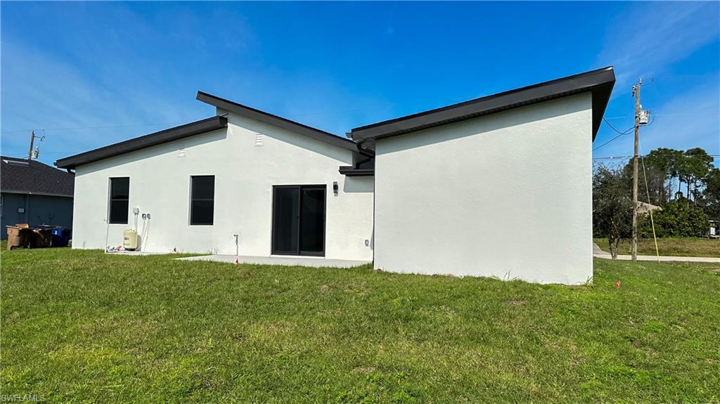 Rear view of property with a yard and stucco siding