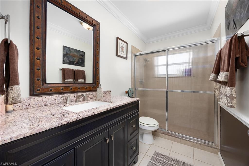 Full bath featuring ornamental molding, vanity, a stall shower, and light tile patterned floors