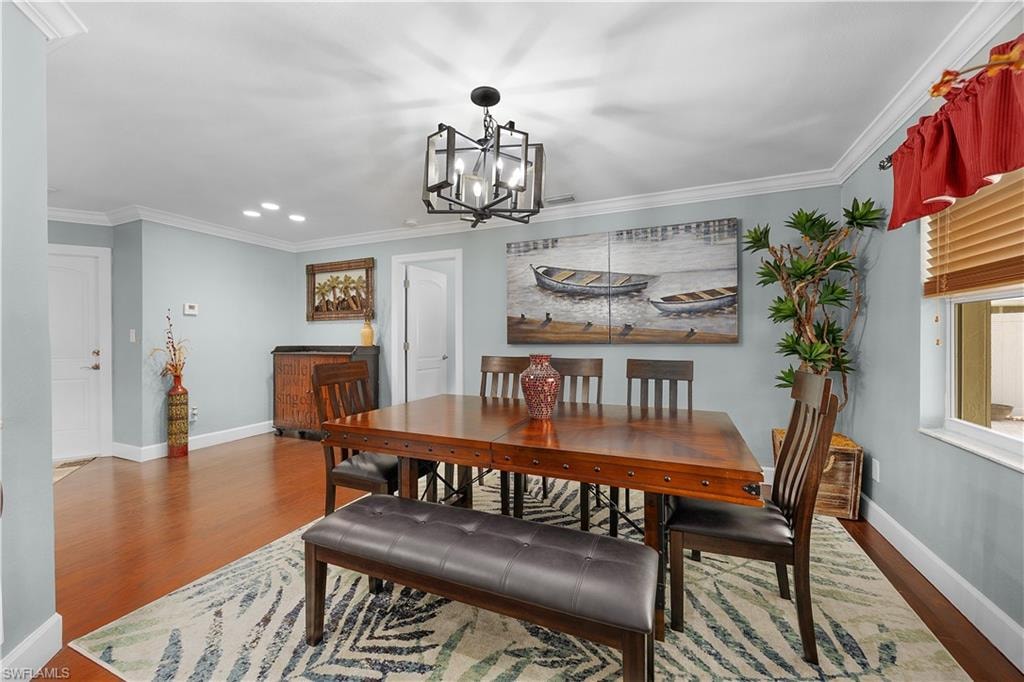 Dining room featuring crown molding, wood finished floors, and hanging lights