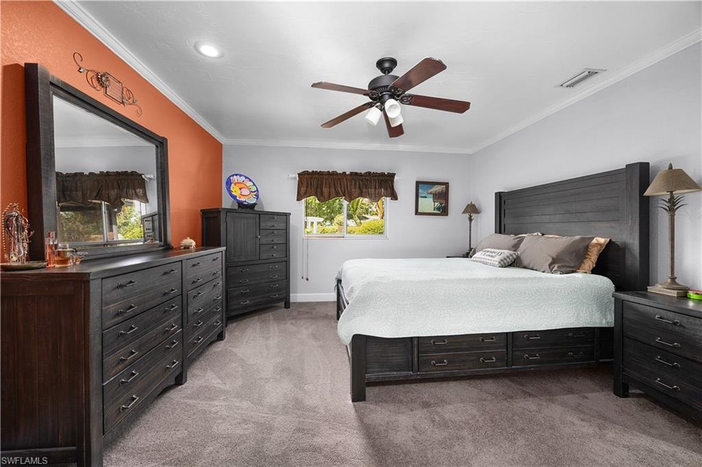 Bedroom featuring light colored carpet, a ceiling fan, and crown molding