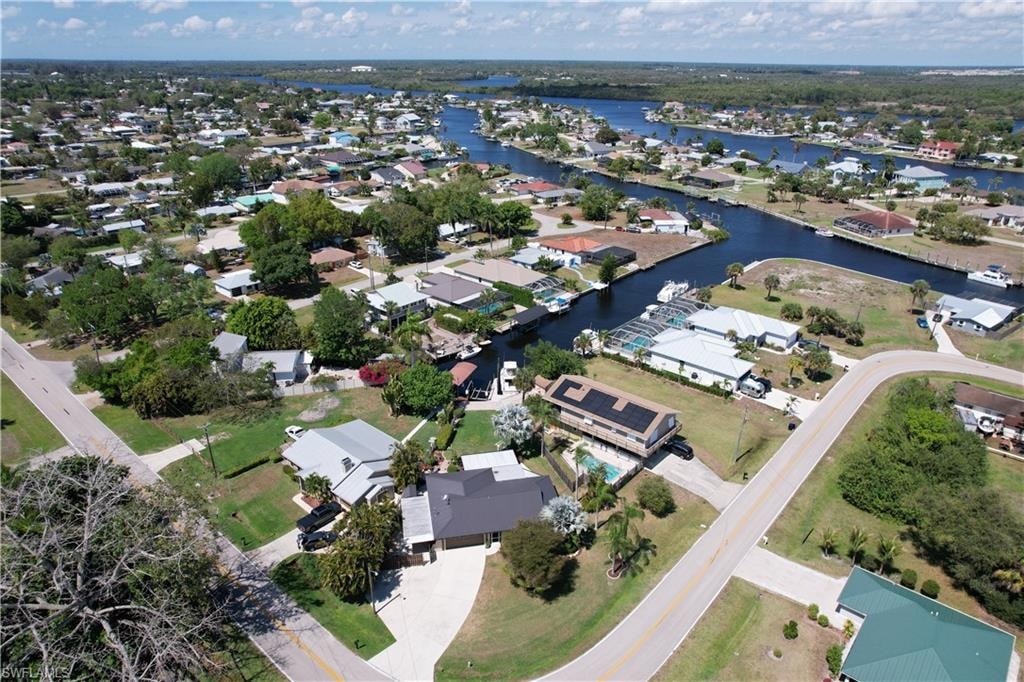 Aerial view of property and surrounding area featuring nearby suburban area and a large body of water