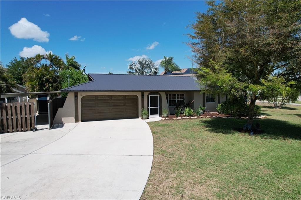 Ranch-style home with an attached garage, concrete driveway, a front lawn, stucco siding, and a metal roof