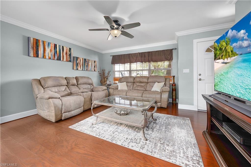 Living area with ornamental molding, dark wood-type flooring, and a ceiling fan